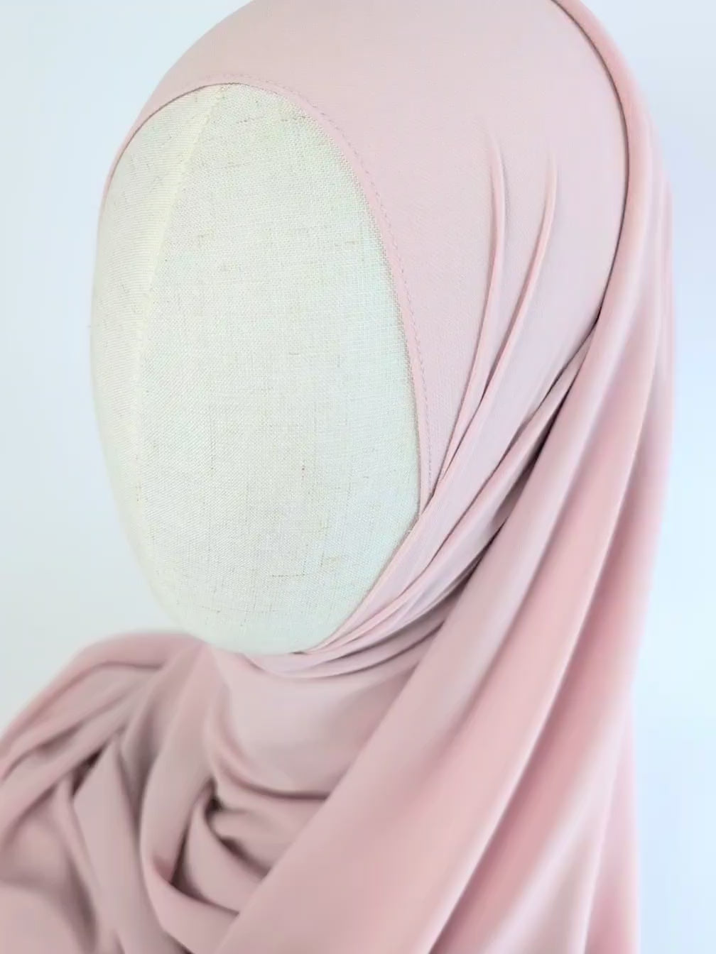 Close-up video of a soft pink or dusty pink color chiffon hijab styled on mannequin head to show the soft texture of the chiffon hijab and  how it would look once styled.