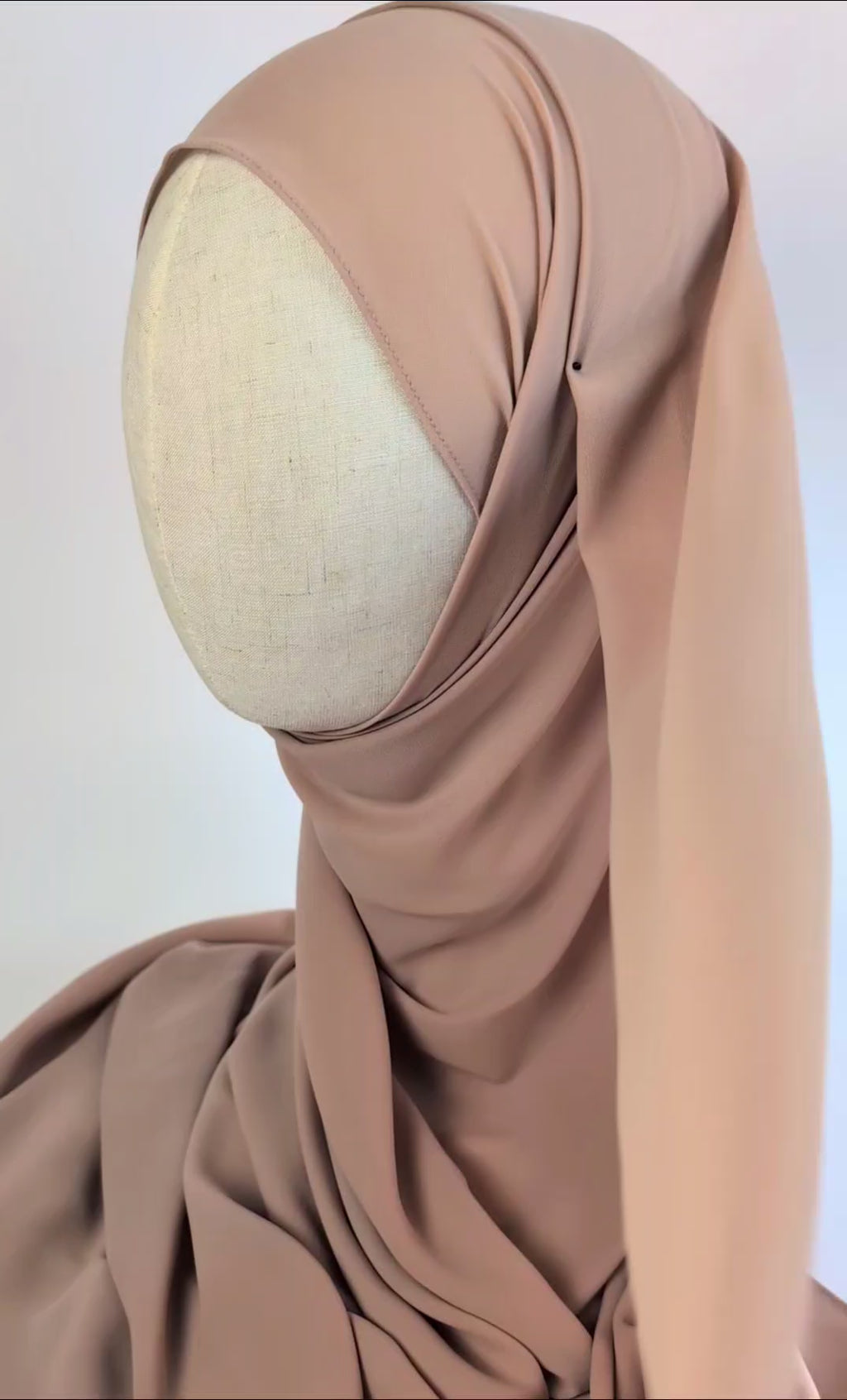 A video of a soft beige color chiffon hijab styled on mannequin head to show the soft texture and the flow and movement of the fabric 