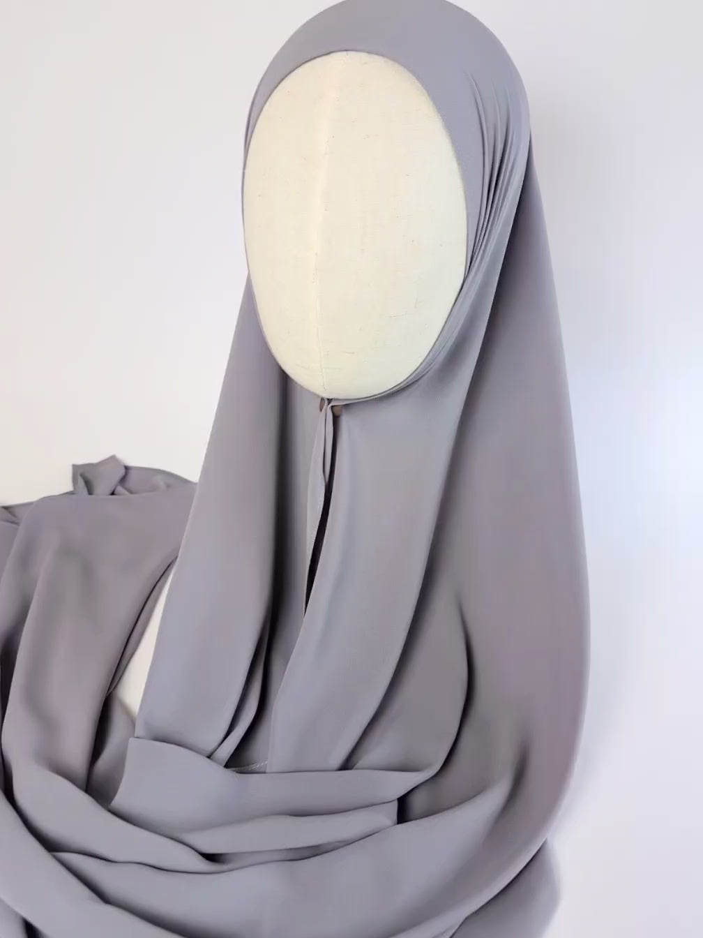 Close-up video of a light gray color chiffon hijab styled on mannequin head to show the soft texture of the chiffon hijab and  how it would look once styled.