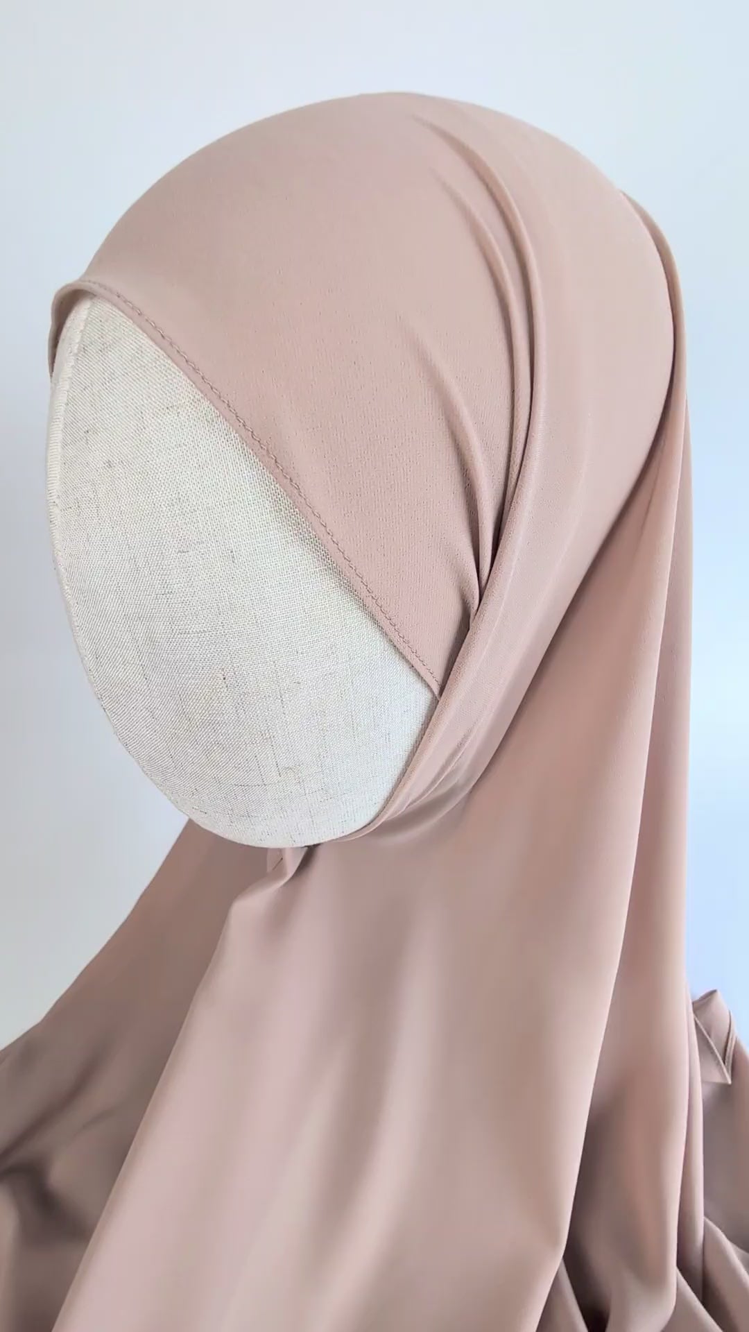 Up to bottom view video of a soft beige color chiffon hijab styled on mannequin head to show the soft texture of the fabric and  how it would look draped and styled