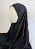 A black chiffon hijab draped over a cream-colored mannequin head in side face shot, photographed against a white background.