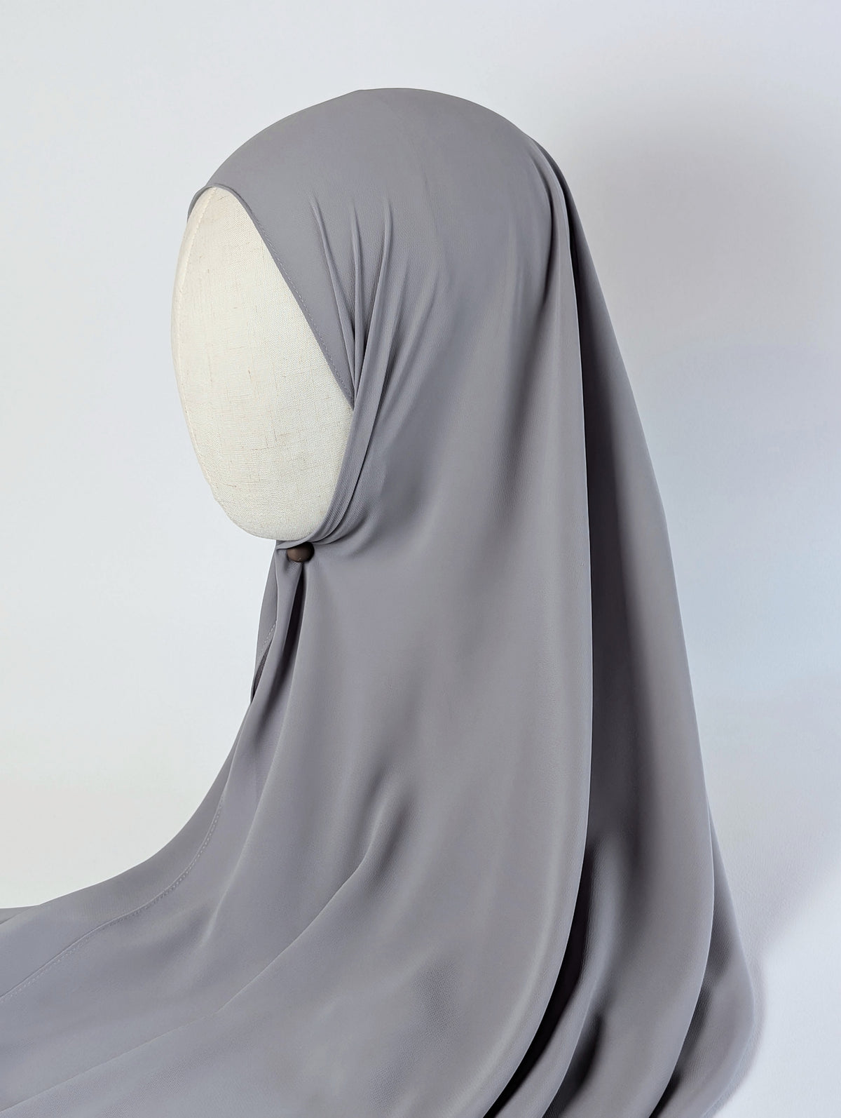 A solid gray chiffon hijab draped over a cream-colored mannequin head in side face shot view, photographed against a white background.